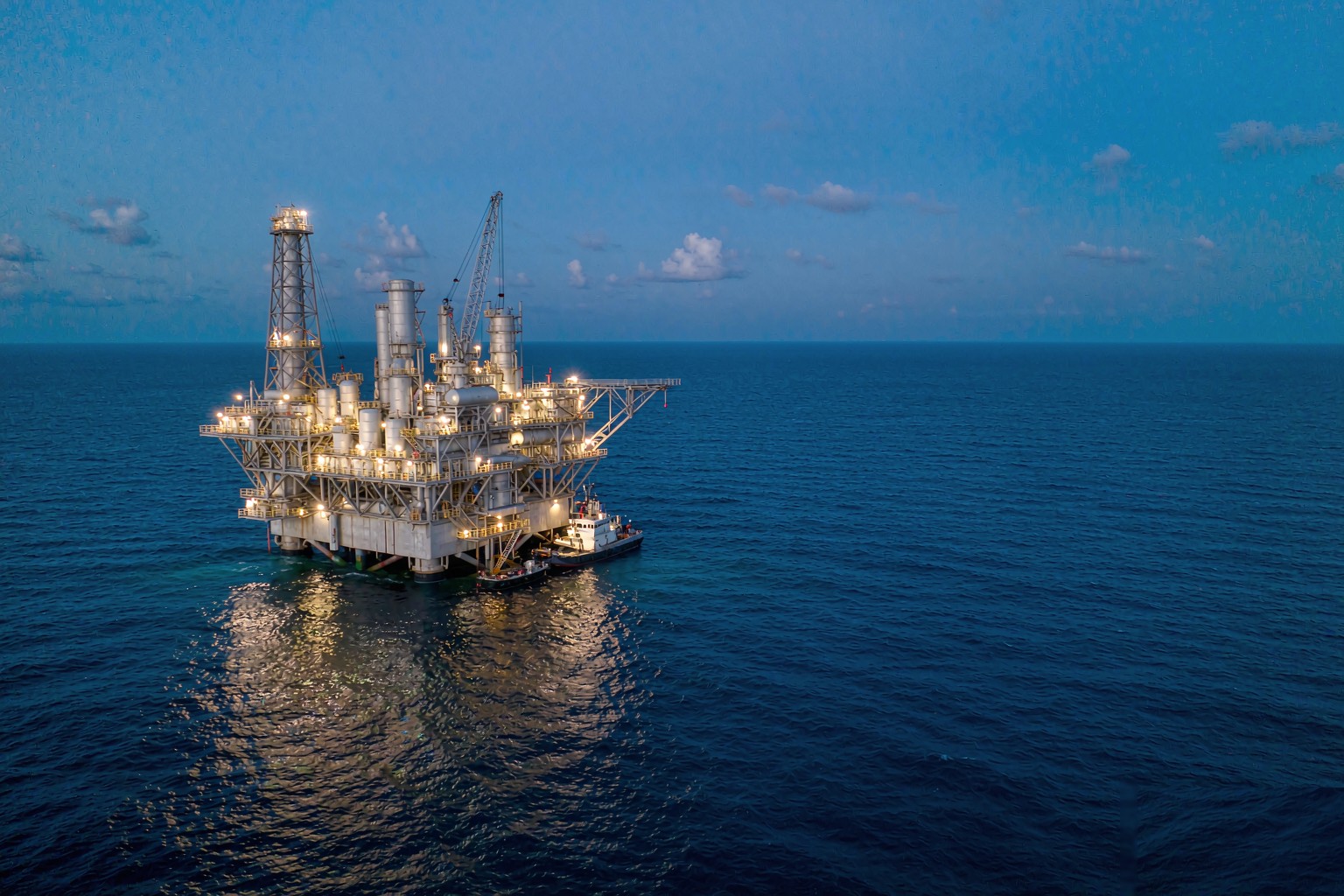 Offshore platform at blue hour with deck floodlights lit across Zone 1 and Zone 2 areas